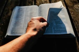 Exploring the Transformational Power of Surrender Open Bible on picnic table with man's hand turning the page