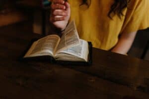 Exploring the Transformational Power of Surrender Lady is turning the pages of a Bible that is sitting on a table