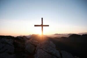 Exploring the Transformational Power of Surrender Cross on mountain of boulders with sunset on horizon