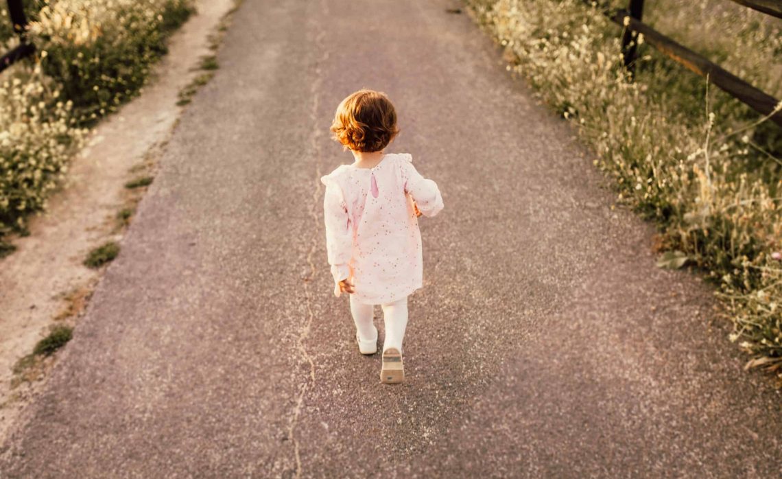 Child walking down a dirt road.